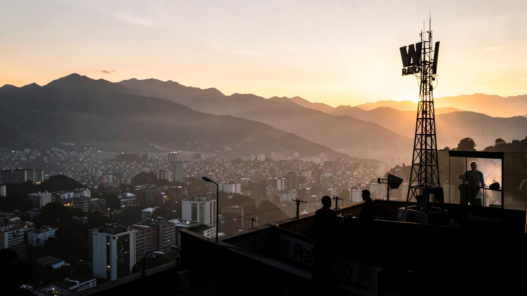 A radio tower silhouetted on a Bogota rooftop with a sign reading W Radio at sunrise