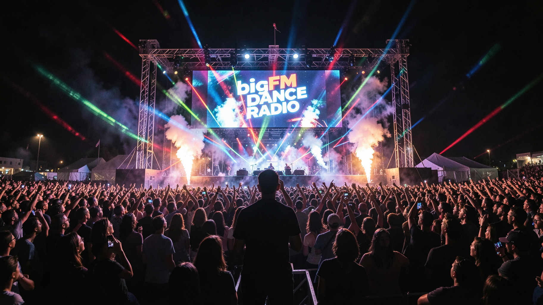 A festival crowd at night with a stage screen reading bigFM Dance Radio