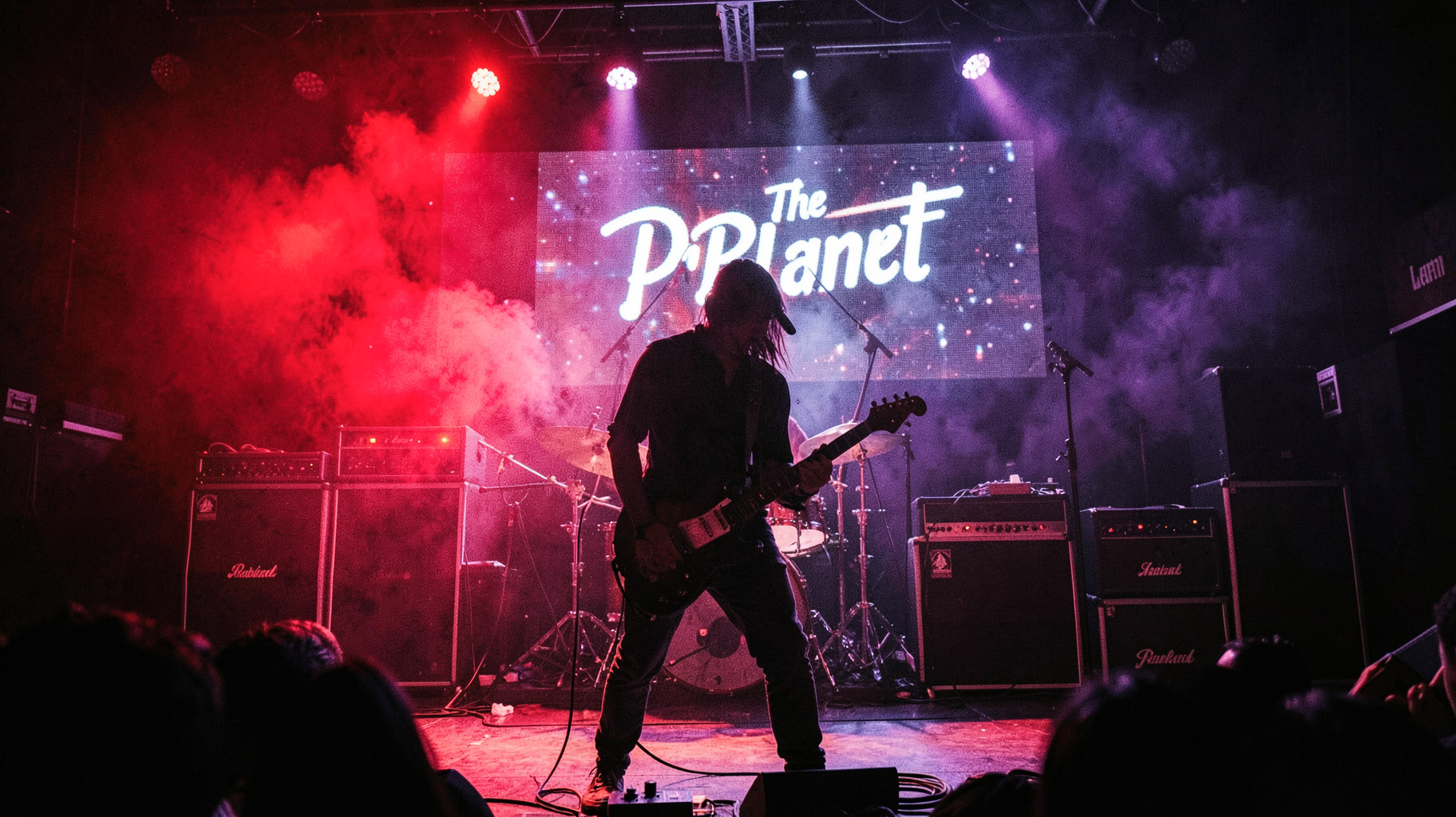 An alternative rock club stage with a screen reading The Planet