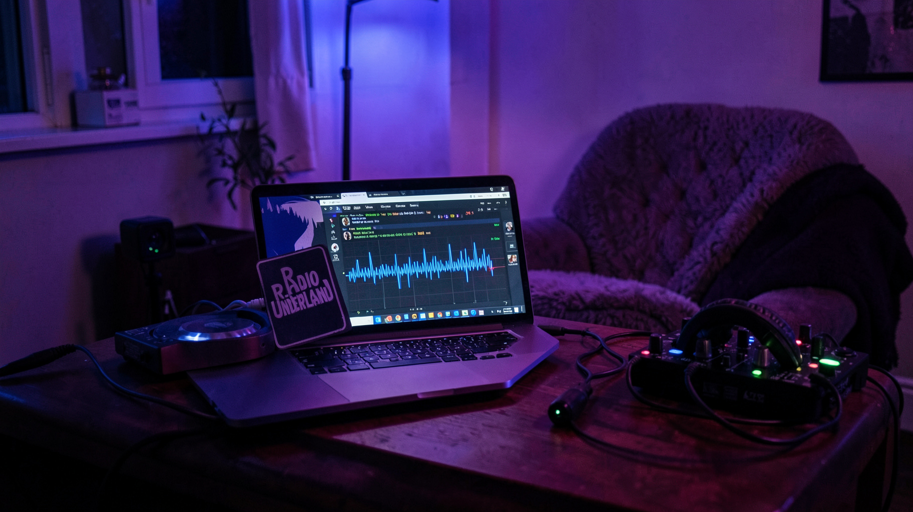 A cozy home bedroom DJ setup at night with RGB lighting and a laptop sticker reading Radio Underland