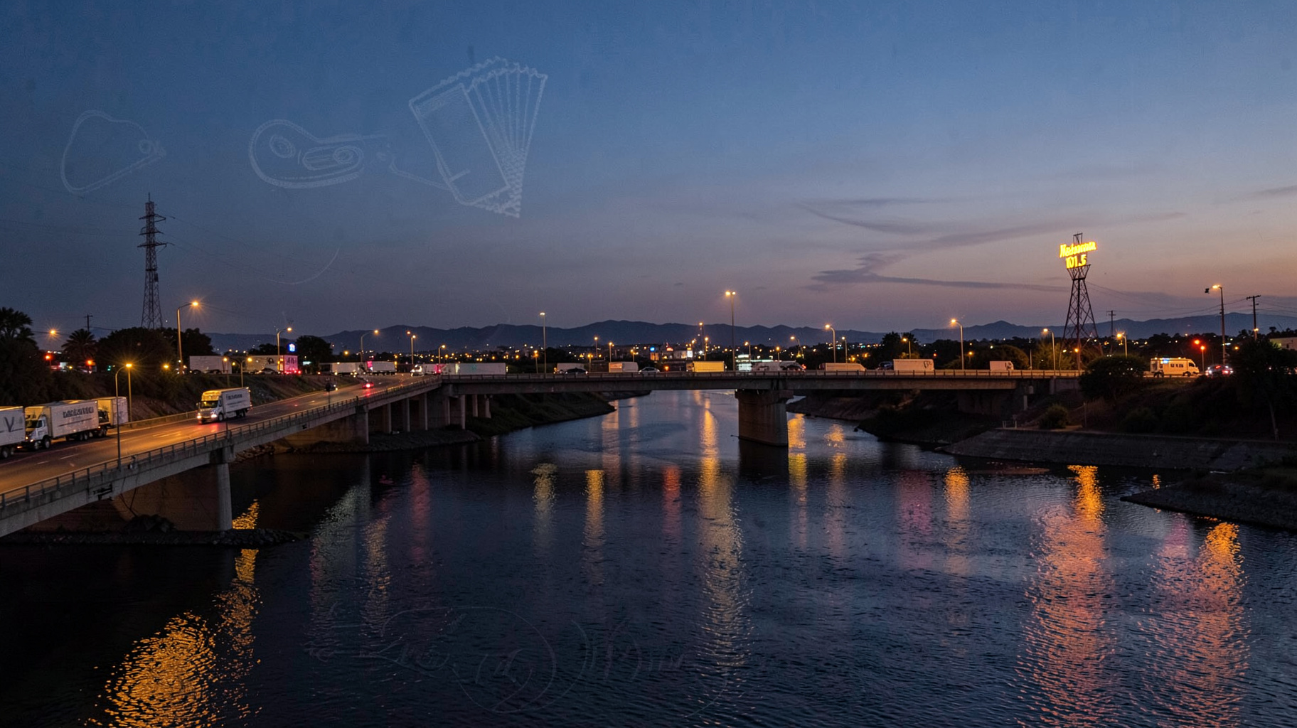 The international bridge between Laredo and Nuevo Laredo at dusk with a sign reading Fiesta Mexicana 101.5