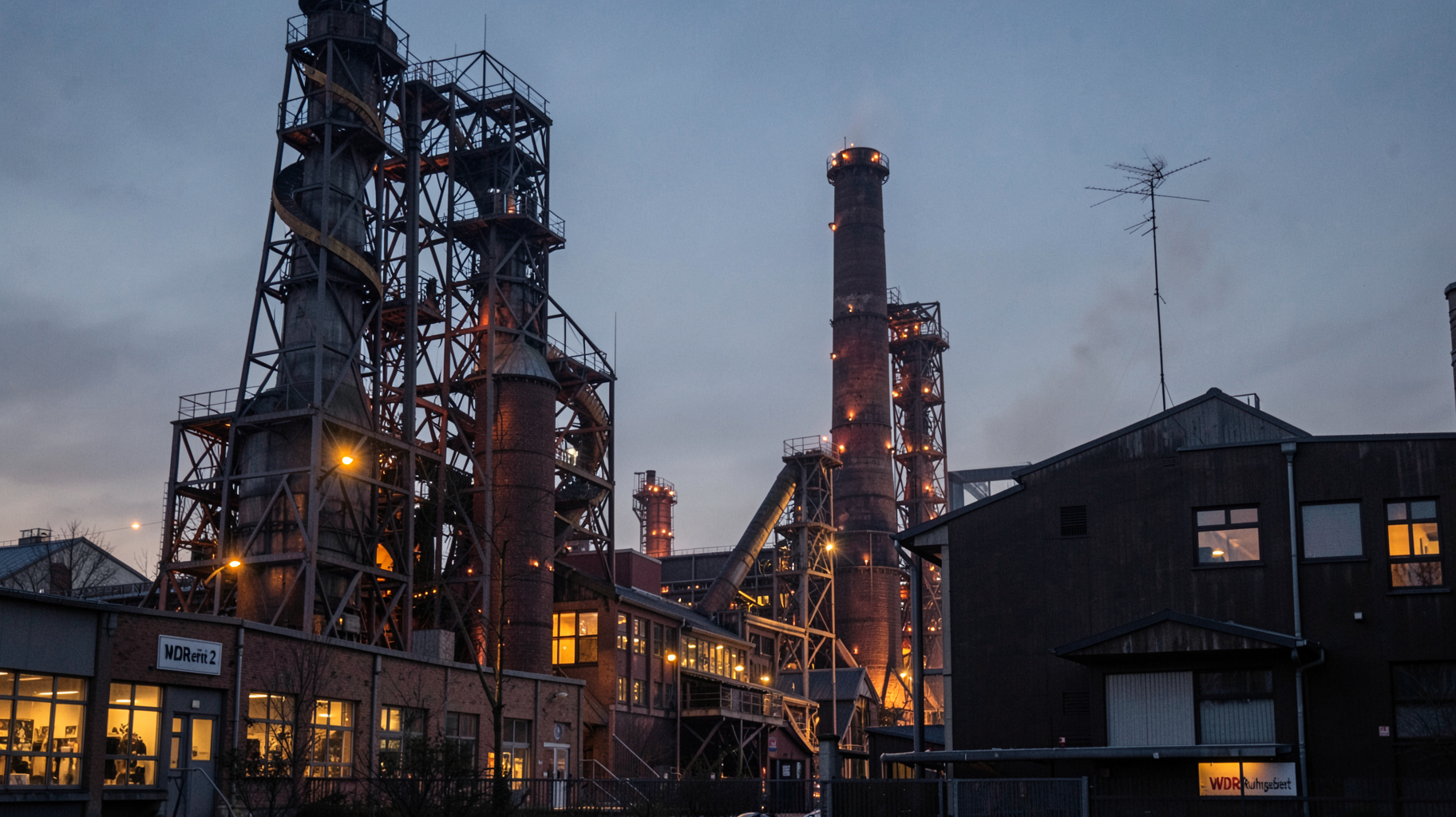 The illuminated Zollverein former coal mine complex in Essen, Germany with a sign reading WDR 2 Ruhrgebiet