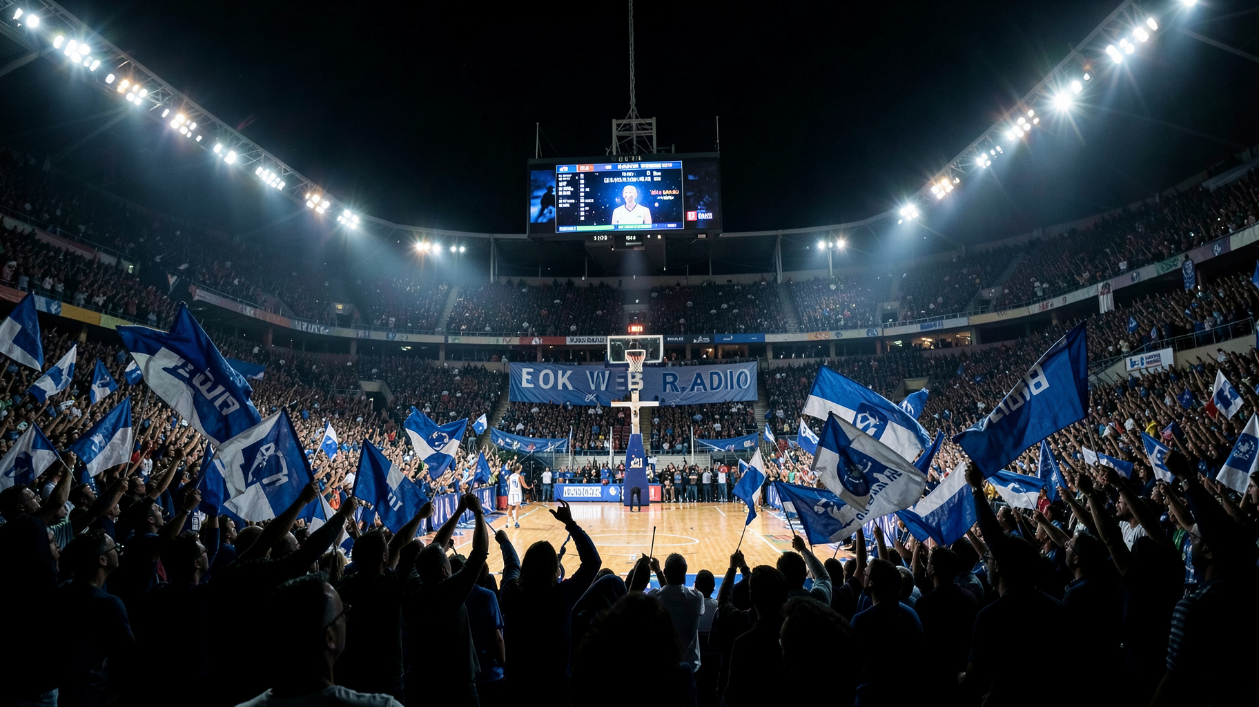 A packed Greek basketball arena at night with a banner reading EOK Web Radio above the court