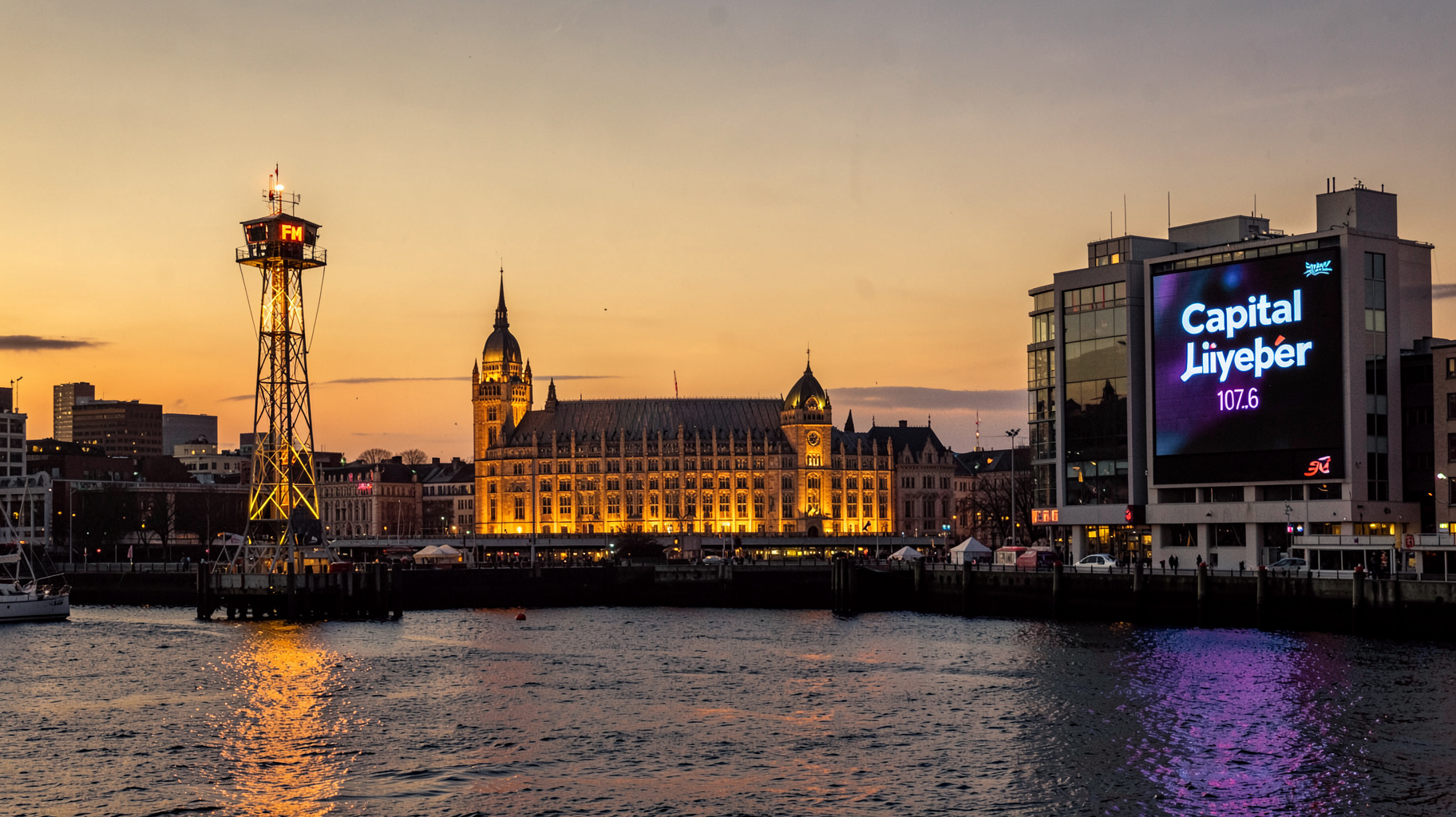 Liverpool waterfront at dusk with a glowing radio tower and a screen displaying Capital Liverpool 107.6