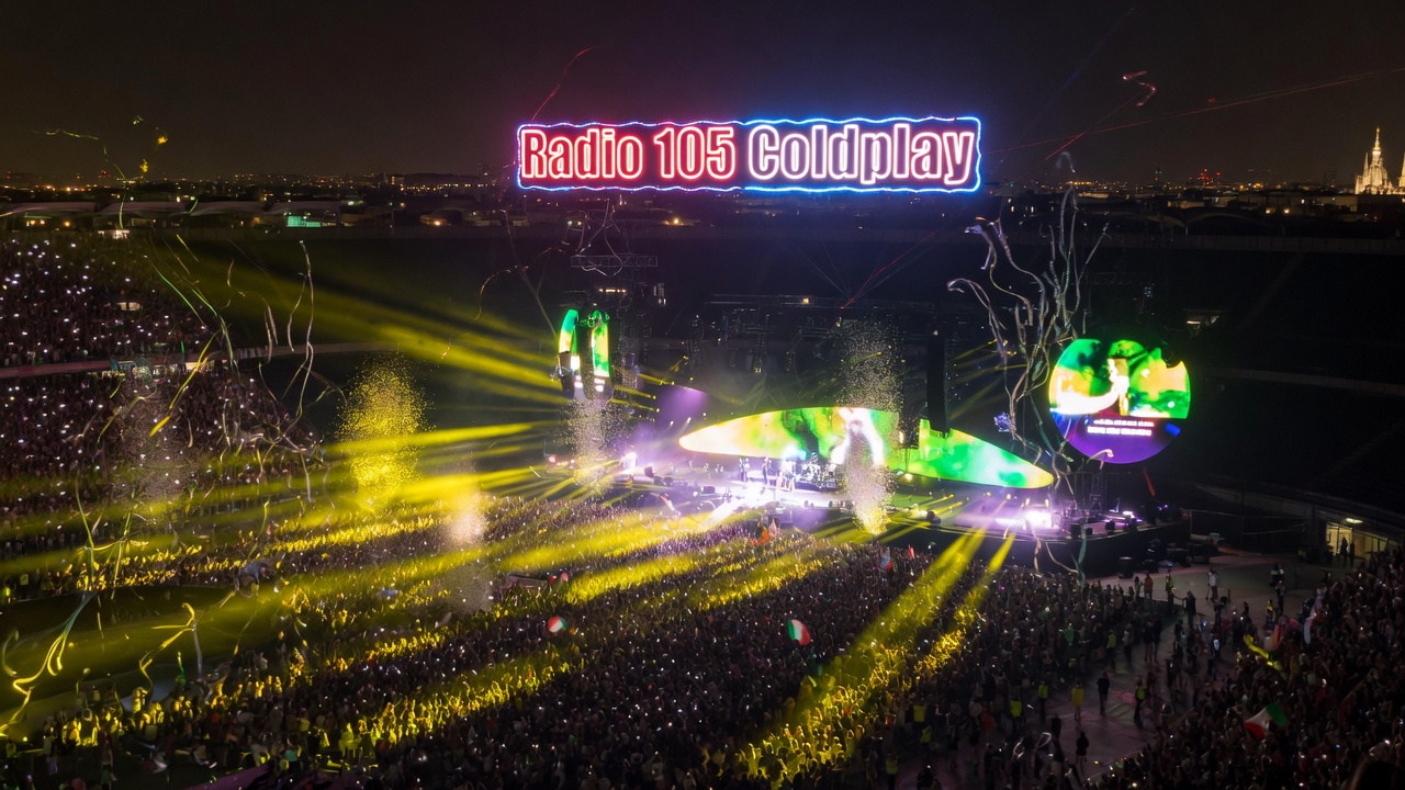 Coldplay stadium concert at night in Milan, neon lights and confetti rain over the crowd