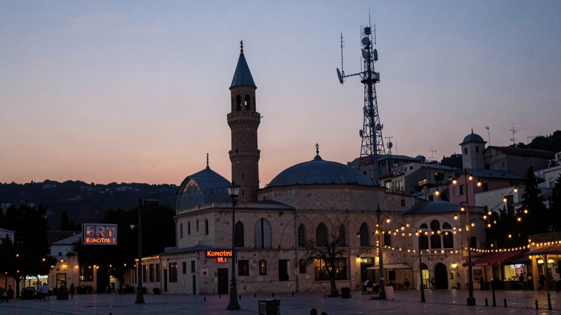 The Imaret Ottoman monument at dusk in Komotini, Greece, with a radio transmitter tower behind it and a sign reading ERT Komotini 98.1