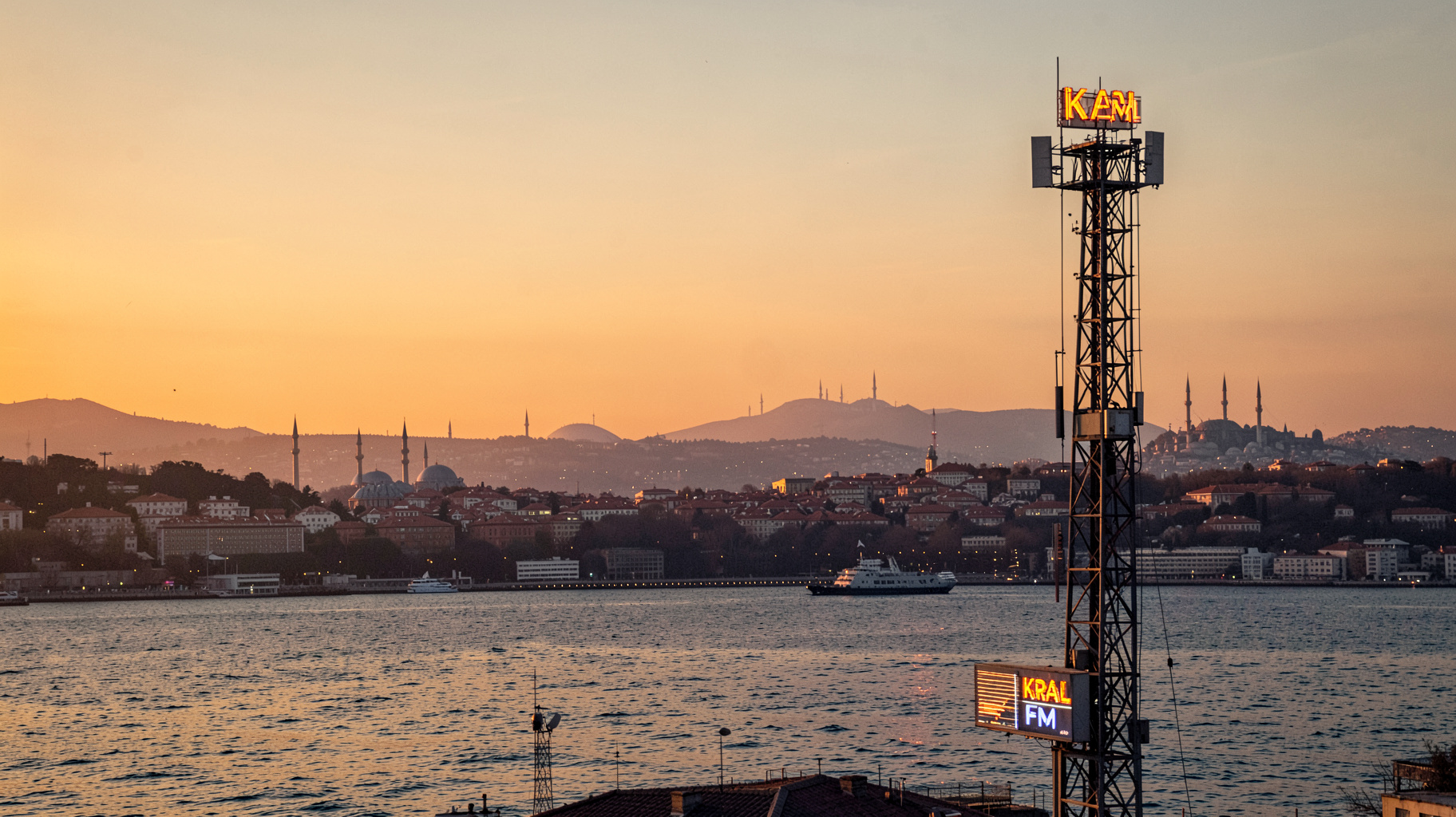 The Istanbul skyline at dusk with a radio broadcast tower and a glowing Kral FM sign