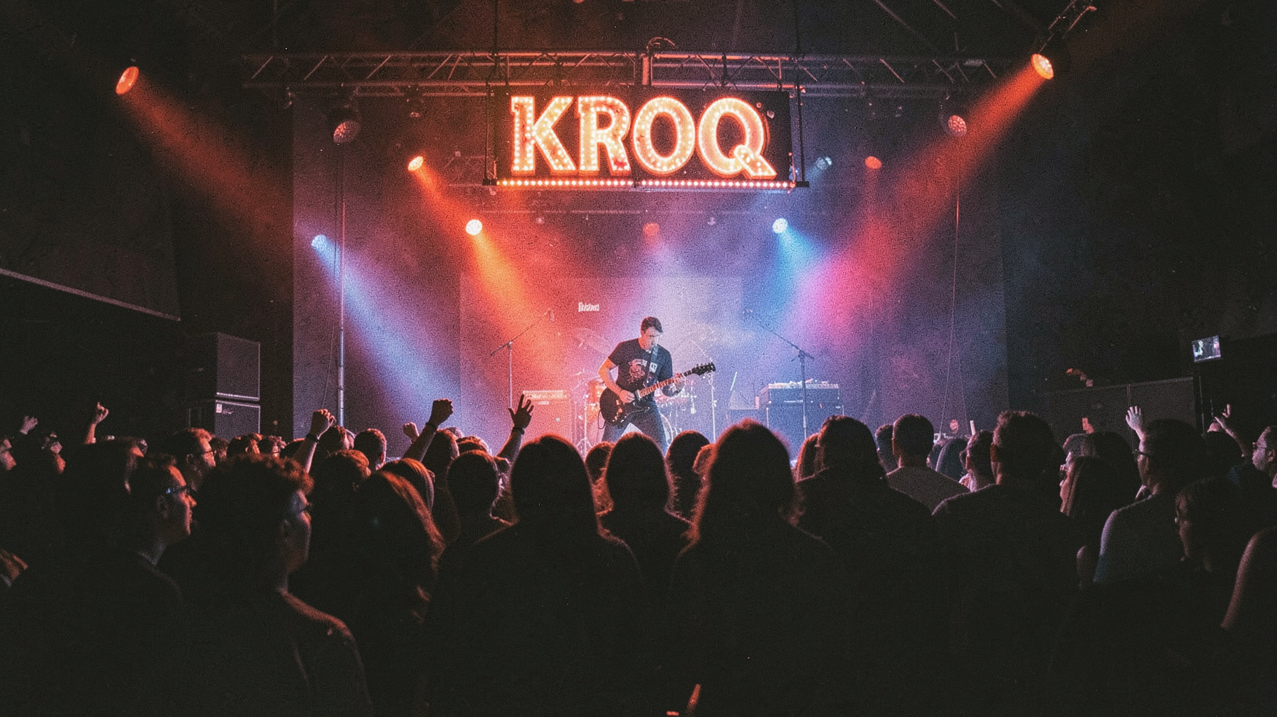 A raw 1980s Los Angeles punk rock club show with a marquee sign reading KROQ