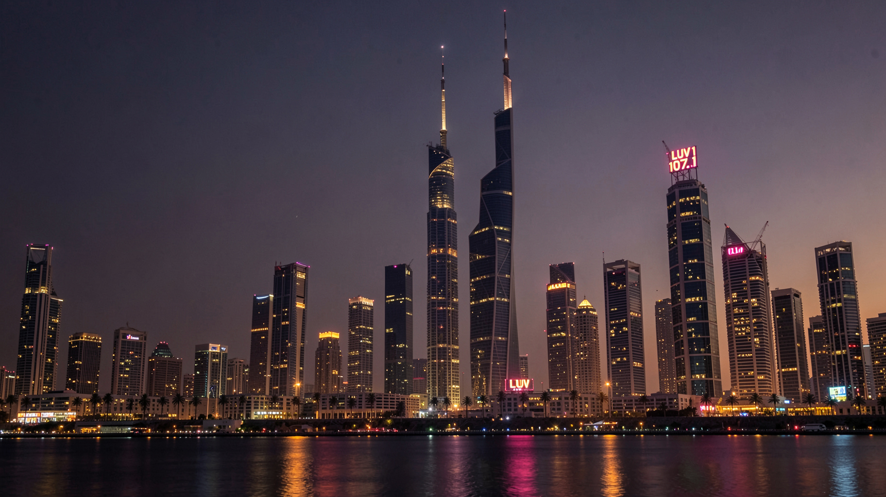 Dubai skyline at dusk with a rooftop sign reading LUV 107.1