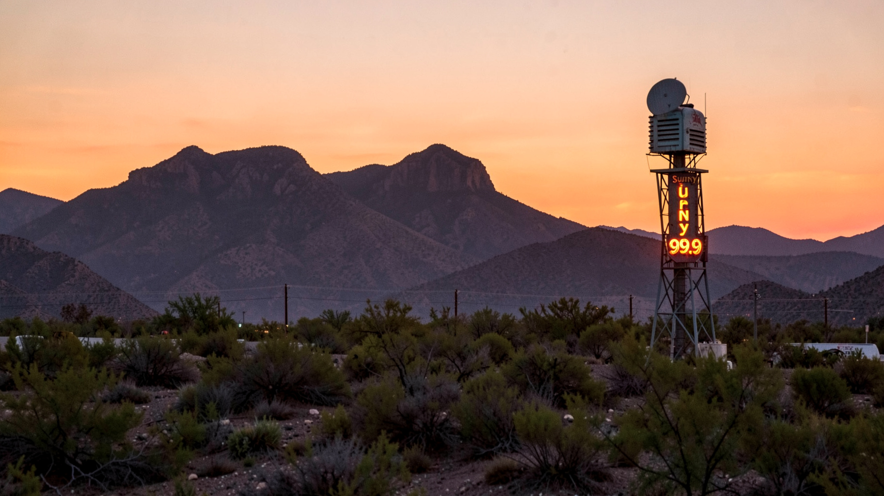 El Paso and Ciudad Juarez border landscape at sunset with a radio tower reading Sunny 99.9
