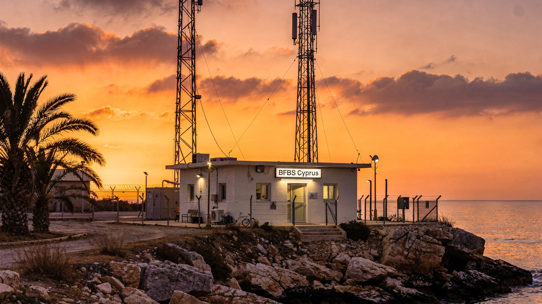 A military radio tower overlooking the Mediterranean coastline of Cyprus at sunset with a sign reading BFBS Cyprus, inspired by BFBS Cyprus