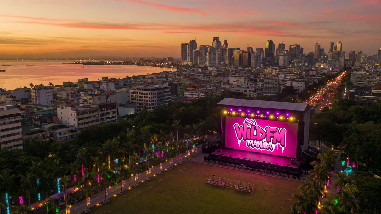 Manila Philippines sunset skyline with an outdoor concert stage and Wild FM Manila LED screen glowing in hot pink and white